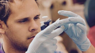 Student looking at chemicals in a vial in lab.