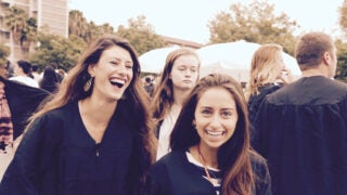 Two students smiling and laughing at Commencement.