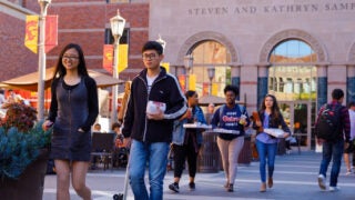 Students walking out of the Ronald Tutor Center after grabbing their lunch on a sunny day.