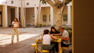 Students discuss artwork in a courtyard with professor.