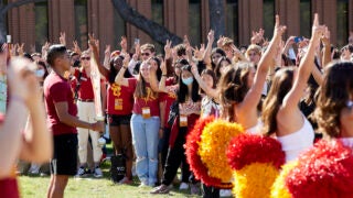 Prospective students holding up Fight On! hand sign with USC Song Girls at Orientation Event.