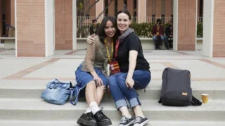 Two students posing for picture while sitting at stairs.