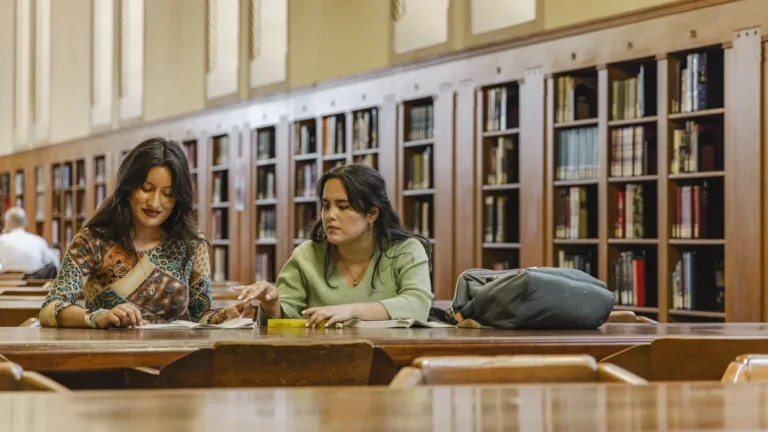 Two students reading together at the library.